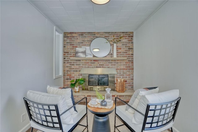 living room featuring hardwood / wood-style flooring, crown molding, and a brick fireplace