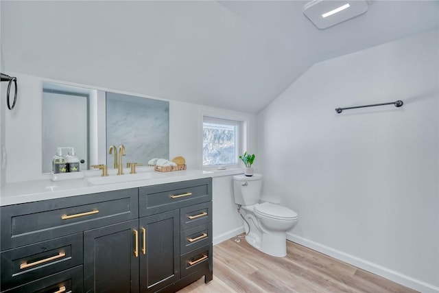 bathroom featuring hardwood / wood-style flooring, lofted ceiling, toilet, and vanity