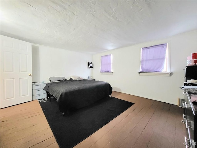 bedroom with dark hardwood / wood-style floors and a textured ceiling