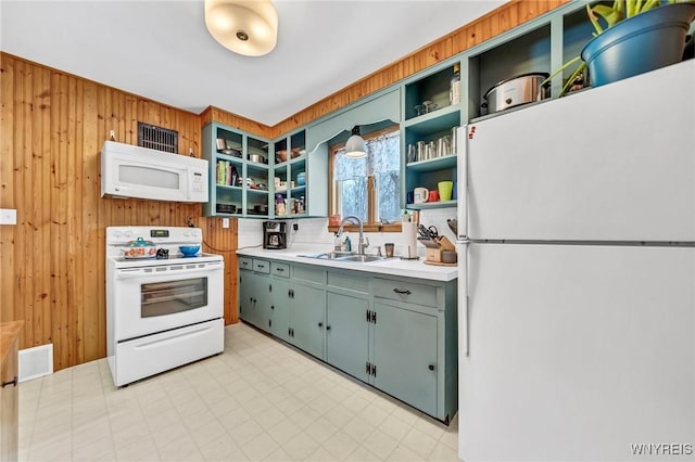 kitchen with sink, white appliances, and wood walls