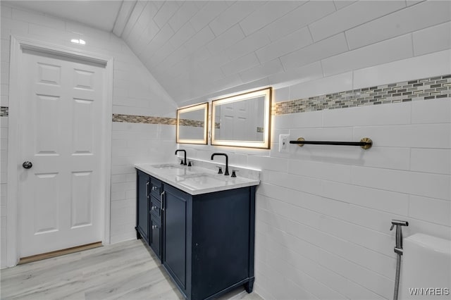 bathroom featuring hardwood / wood-style flooring, lofted ceiling, vanity, and tile walls