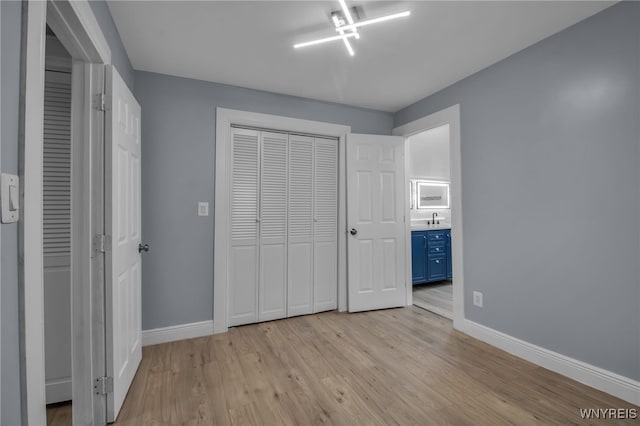 unfurnished bedroom featuring sink, light hardwood / wood-style floors, and a closet