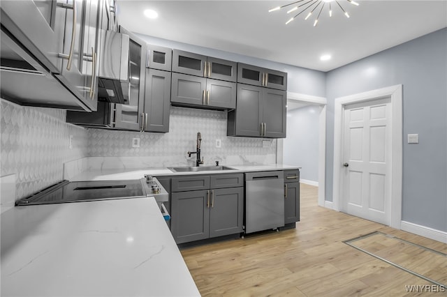 kitchen with sink, gray cabinetry, light stone counters, light hardwood / wood-style floors, and stainless steel dishwasher