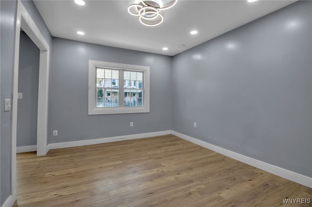 empty room featuring an inviting chandelier and light hardwood / wood-style flooring