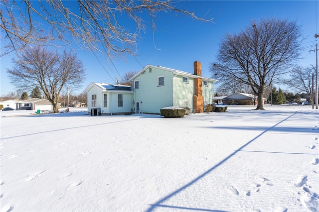 snow covered house featuring cooling unit