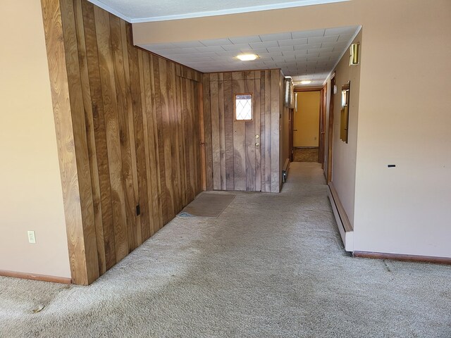 corridor with crown molding, light colored carpet, and wood walls