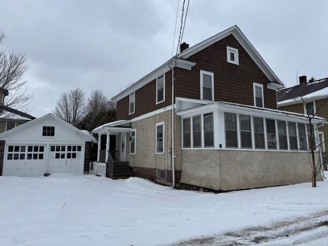 view of snow covered exterior with a garage and an outdoor structure