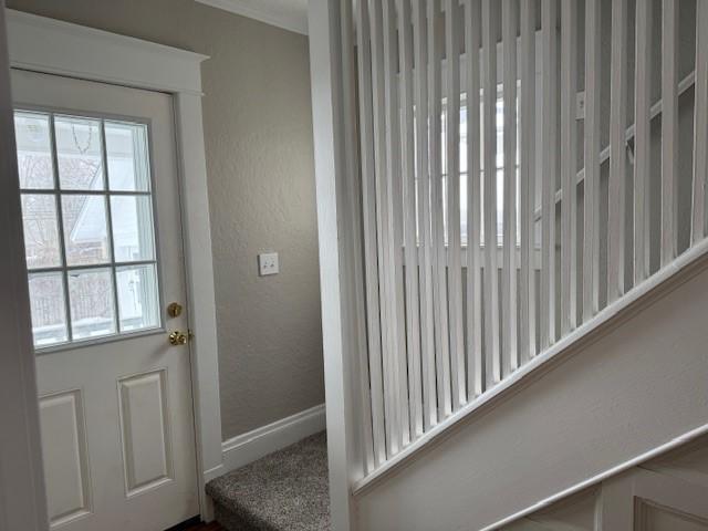 doorway to outside featuring baseboards and a textured wall