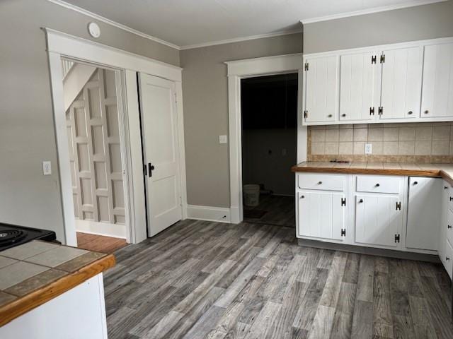 kitchen featuring ornamental molding, tasteful backsplash, wood finished floors, white cabinetry, and tile countertops