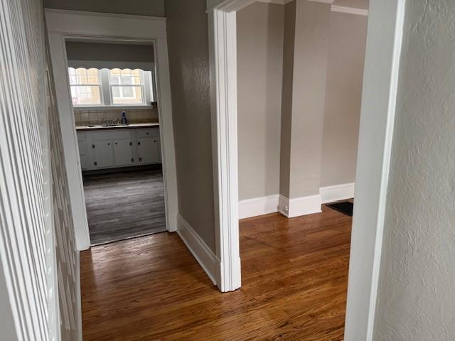 hallway featuring baseboards and dark wood-style floors