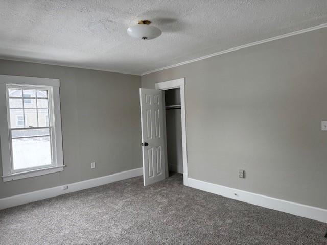 unfurnished bedroom featuring ornamental molding, a textured ceiling, a closet, carpet floors, and baseboards