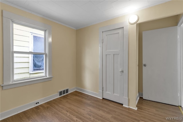 empty room featuring crown molding, a healthy amount of sunlight, and light wood-type flooring