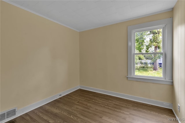 empty room with hardwood / wood-style floors and crown molding