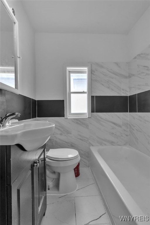 bathroom featuring tile walls, vanity, toilet, and a bathing tub