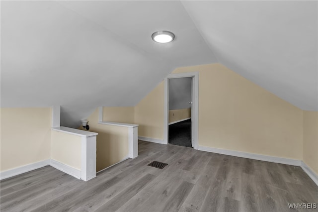 additional living space with light hardwood / wood-style flooring and vaulted ceiling