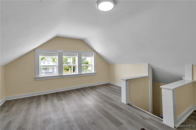 bonus room with vaulted ceiling and light wood-type flooring