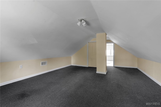 bonus room with dark colored carpet and lofted ceiling