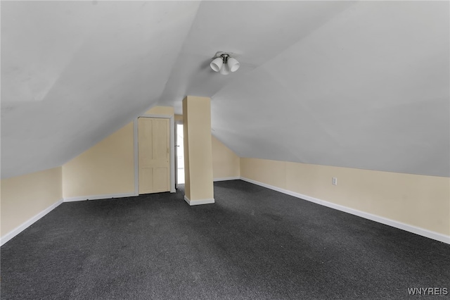 additional living space featuring dark colored carpet and lofted ceiling