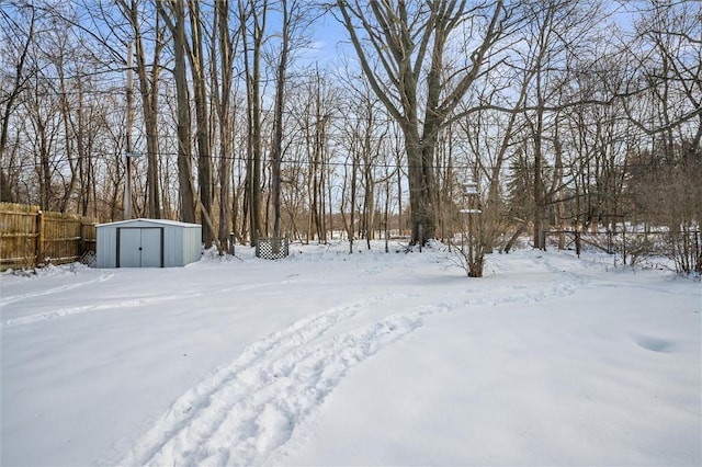 snowy yard featuring a storage shed