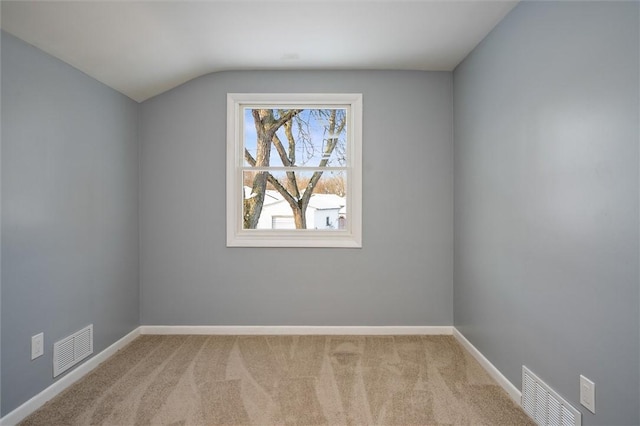 carpeted spare room with vaulted ceiling