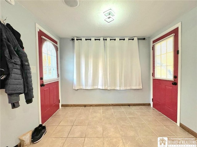 foyer entrance with light tile patterned floors and a textured ceiling