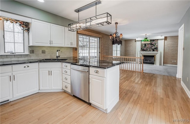 kitchen with decorative light fixtures, dishwasher, sink, and white cabinets