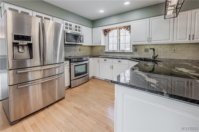 kitchen featuring sink, dark stone countertops, white cabinets, kitchen peninsula, and stainless steel appliances