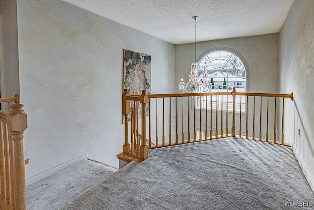 corridor featuring a notable chandelier, carpet floors, and a textured ceiling