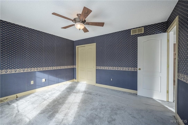 spare room featuring ceiling fan, carpet flooring, and a textured ceiling