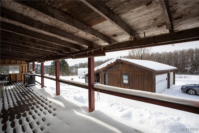 snow covered patio featuring grilling area and a garage