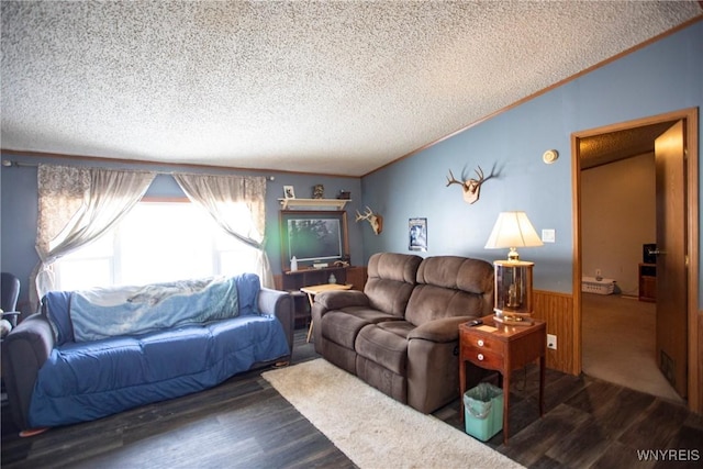 living room featuring crown molding, dark hardwood / wood-style flooring, a textured ceiling, and wood walls