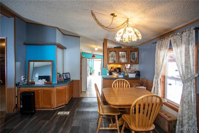 dining space featuring dark hardwood / wood-style floors, an inviting chandelier, lofted ceiling, ornamental molding, and a textured ceiling