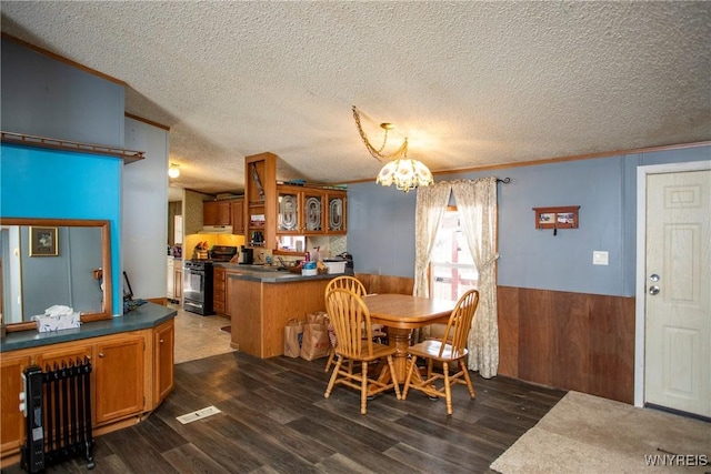 dining area featuring crown molding, wooden walls, dark hardwood / wood-style floors, and a textured ceiling