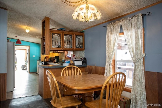 dining space with lofted ceiling, a notable chandelier, crown molding, and plenty of natural light