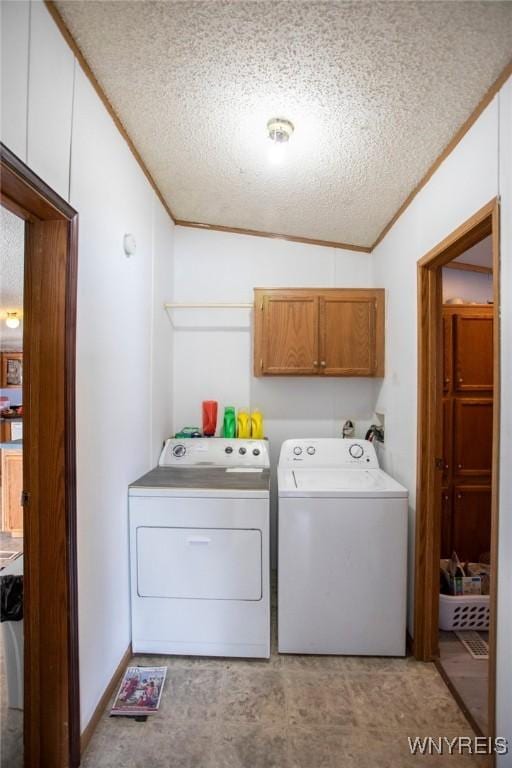 clothes washing area with cabinets, crown molding, a textured ceiling, and washer and clothes dryer