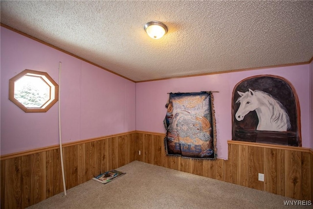 carpeted empty room featuring wooden walls, a textured ceiling, and vaulted ceiling