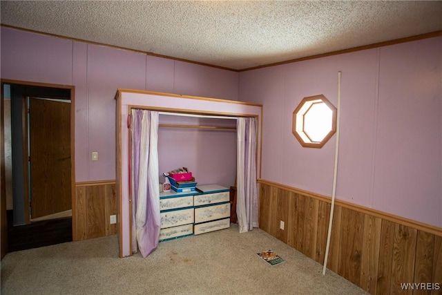 carpeted bedroom with wooden walls, a textured ceiling, and a closet