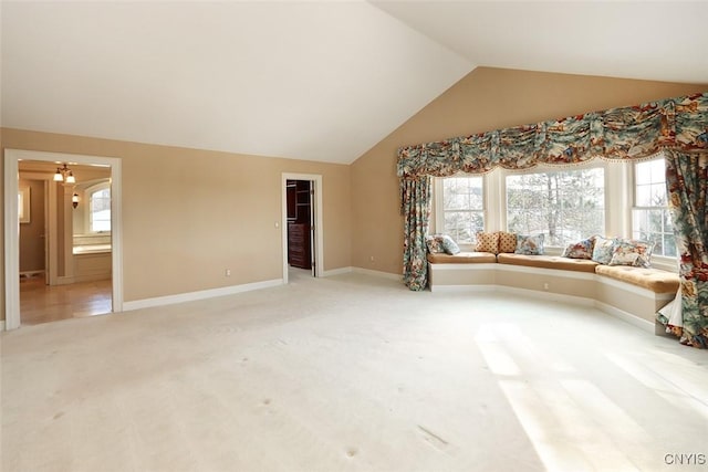 unfurnished living room with vaulted ceiling, plenty of natural light, and carpet floors