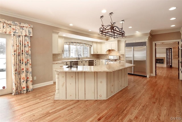 kitchen with stove, a center island, light stone counters, light hardwood / wood-style floors, and stainless steel built in fridge