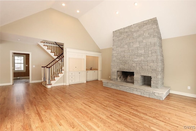 unfurnished living room with a stone fireplace, light hardwood / wood-style floors, and high vaulted ceiling