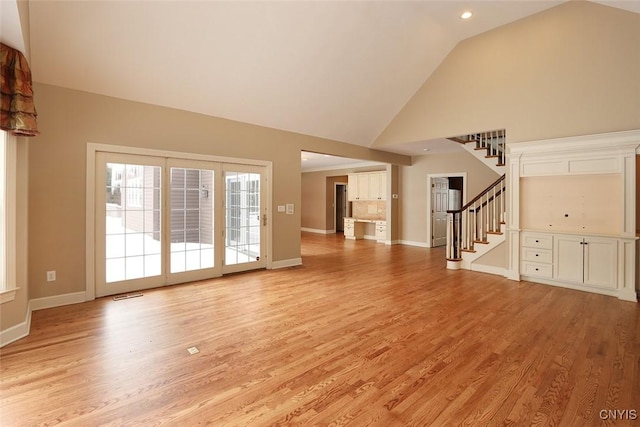 unfurnished living room with high vaulted ceiling and light hardwood / wood-style floors