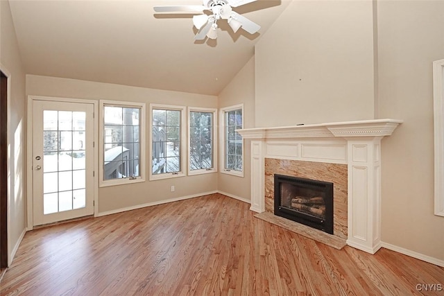 unfurnished living room featuring ceiling fan, lofted ceiling, a fireplace, and light hardwood / wood-style floors