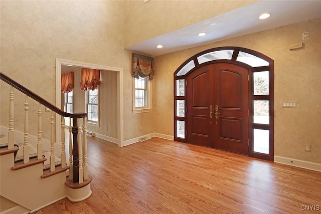 entrance foyer featuring a towering ceiling and light hardwood / wood-style flooring