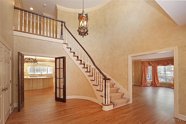 stairway featuring crown molding, sink, hardwood / wood-style flooring, and a high ceiling