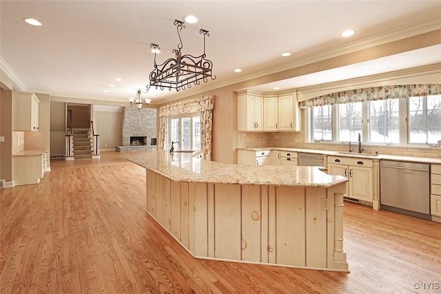 kitchen featuring light stone countertops, sink, stainless steel dishwasher, and cream cabinets