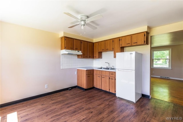 kitchen with sink, dark hardwood / wood-style floors, white fridge, ceiling fan, and decorative backsplash