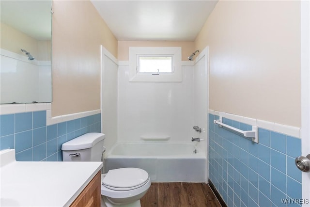 full bathroom with toilet, tile walls, vanity, shower / washtub combination, and hardwood / wood-style flooring