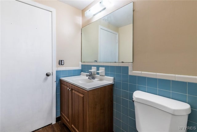 bathroom with vanity, toilet, and tile walls