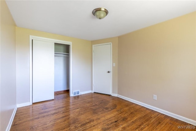 unfurnished bedroom with dark wood-type flooring and a closet