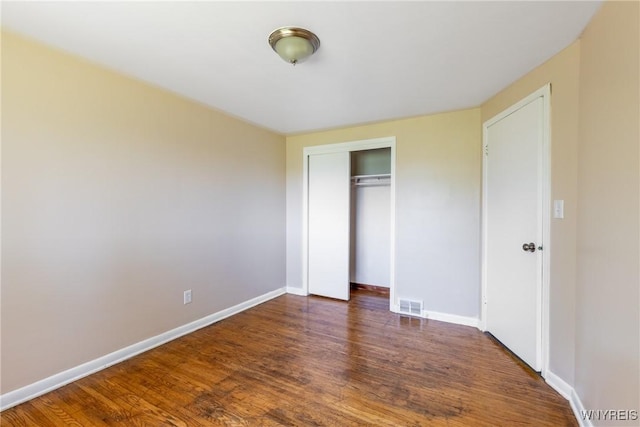 unfurnished bedroom with dark hardwood / wood-style flooring and a closet